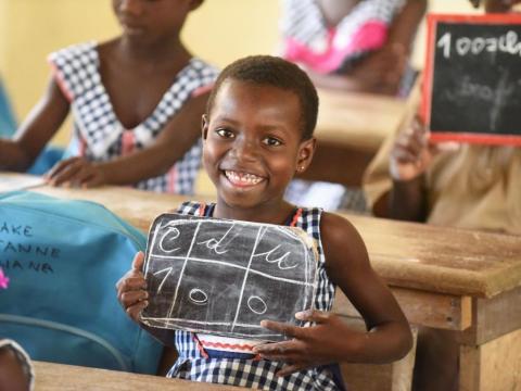 A UNICEF photo showing a happy looking school girl displaying a slate