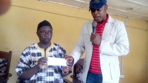 Tom Issic Tucker, MP, handing cheque to Chief Philip Musa Koroma of Nimiyama Chiefdom